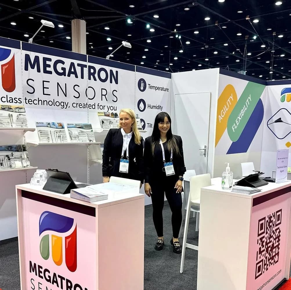 Megatron Sensors exhibit with two booth staff between branded counters
