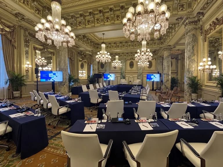 Board meeting tables set inside an ornate room with chandeliers