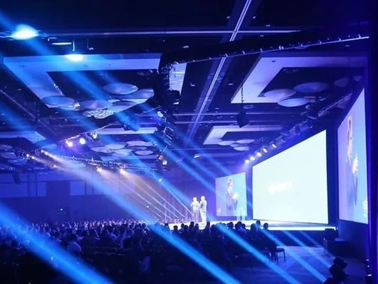 Medallia Experience stage with blue lighting and a large seated audience