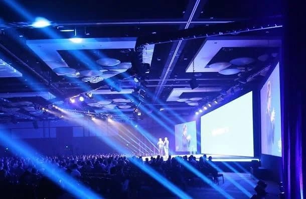 Medallia Experience stage with blue lighting and a large seated audience